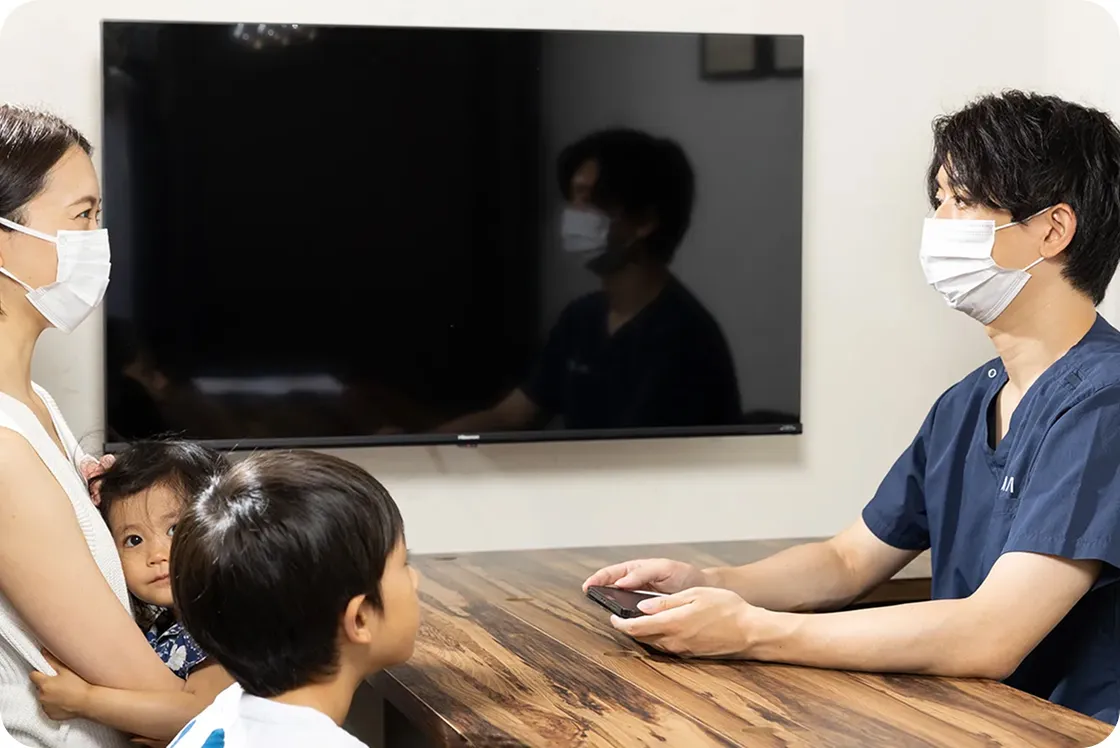 歯科医師が親子に治療内容を説明しているカウンセリング風景