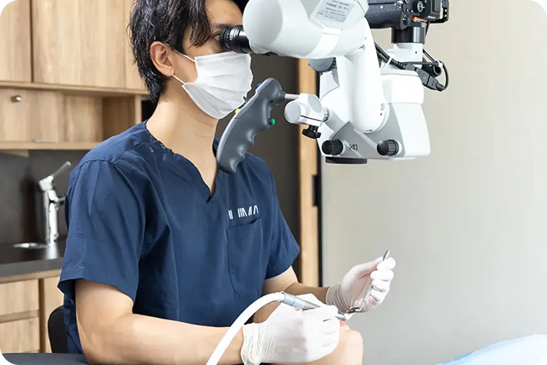 マイクロスコープを使って精密治療を行う歯科医師
