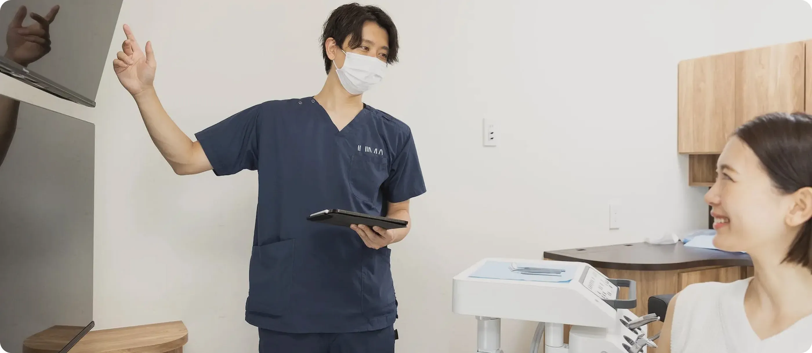 タブレットを使って治療内容を説明する歯科医師と患者